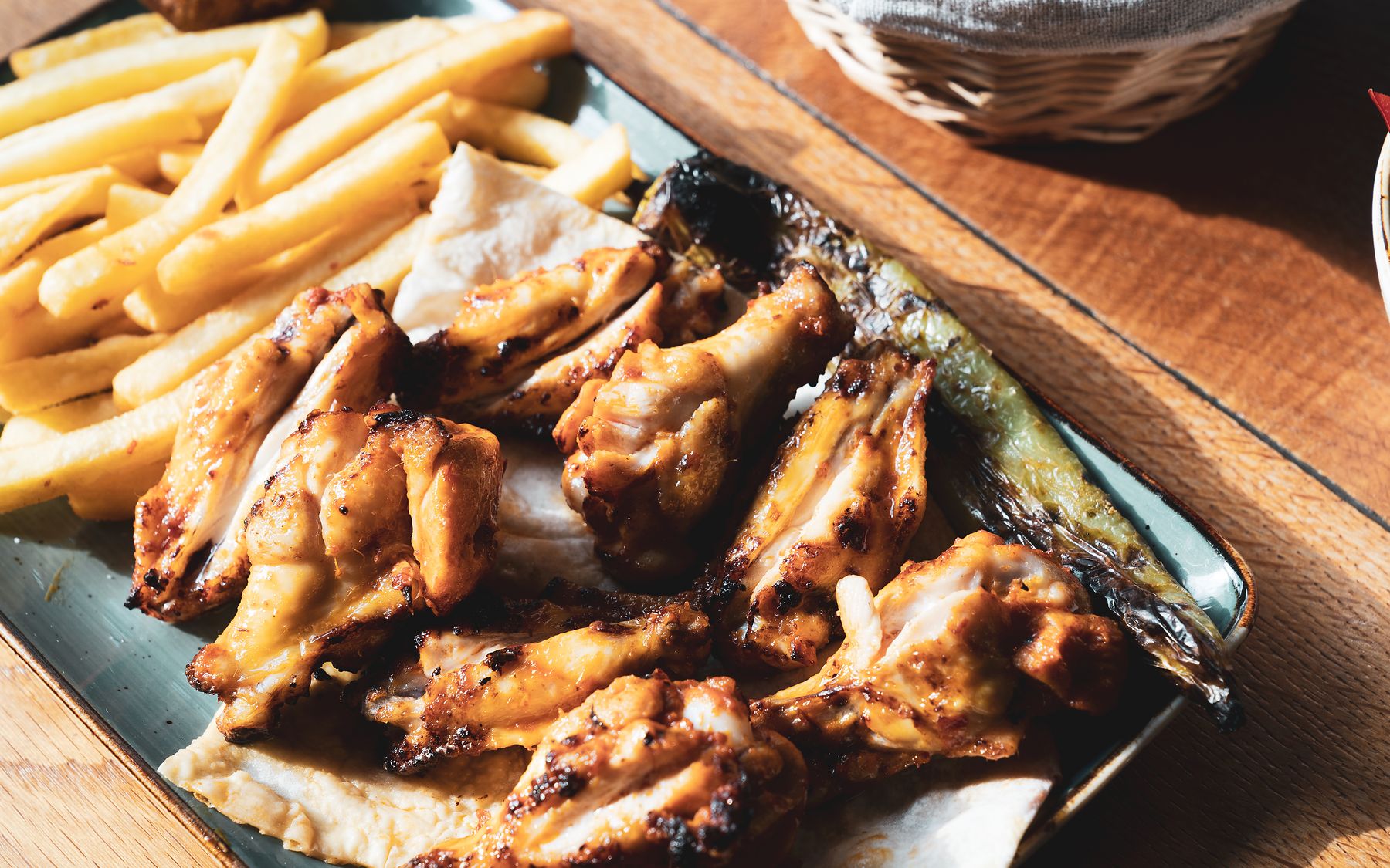 Gegrillte Hähnchenflügel vom Holzkohlegrill mit Pommes frites